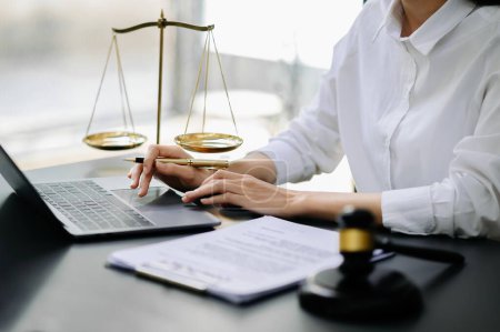 Foto de Justice and law concept.female judge in a courtroom  the gavel, working with  laptop and digital tablet computer on table in morning light - Imagen libre de derechos