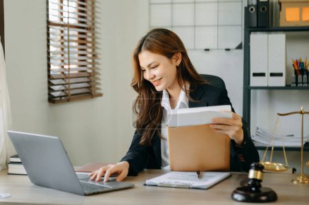 Foto de Attractive young lawyer in office. Business woman and lawyers discussing contract papers laptop and tablet with brass scale on  desk in modern office. Law, legal services, advice, - Imagen libre de derechos
