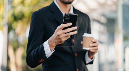 Téléchargez les photos : Businessman using digital tablet, smartphone and holding coffee to go while working at office - en image libre de droit