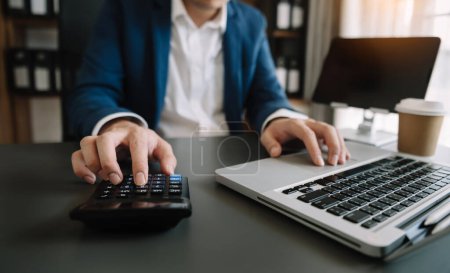 Téléchargez les photos : Close up of businessman or accountant hand typing laptop working to calculate on desk about cost at home office - en image libre de droit
