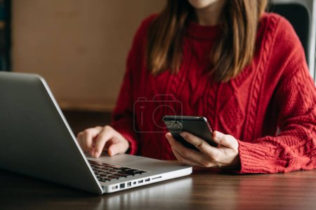 Photo for Businesswoman hand using smart phone and laptop.  payments , online shopping, omni channel,  at office in sunlight - Royalty Free Image
