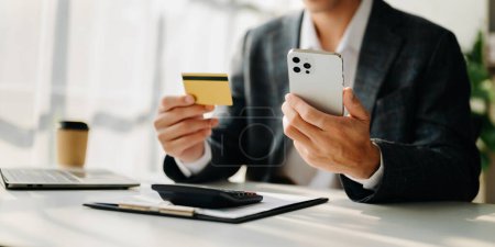Photo for Man using smart phone for mobile payments online shopping,omni channel,sitting on table,virtual icons graphics interface screen - Royalty Free Image