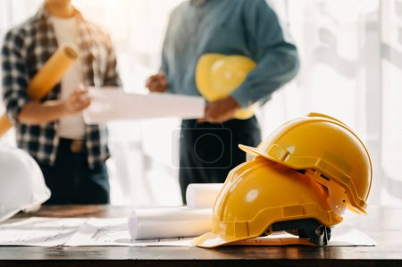Photo for Engineer desk with object paper and tablet with blurry engineer teamwork hardworking to consults about their building project. in office - Royalty Free Image