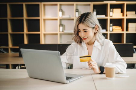 Téléchargez les photos : Femme d'affaires utilisant un ordinateur portable et une carte de crédit pour faire du shopping en ligne au bureau. - en image libre de droit
