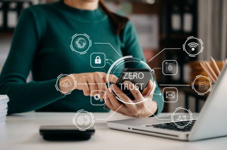 Concept de sécurité zéro confiance, femme utilisant un ordinateur portable et un téléphone avec icône de confiance zéro sur l'écran virtuel de Data businesses.in bureau