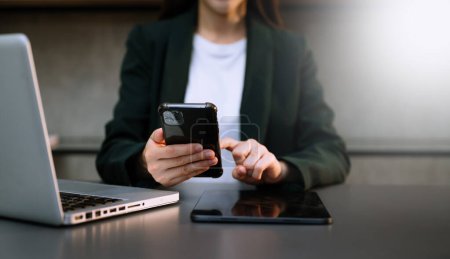 Téléchargez les photos : Femme d'affaires avec ordinateur portable et téléphone intelligent et tablette PC dans le bureau - en image libre de droit