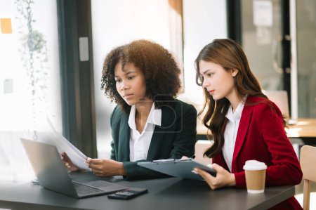 Téléchargez les photos : Deux femmes d'affaires travaillant ensemble avec un ordinateur portable dans un bureau moderne avec du café - en image libre de droit