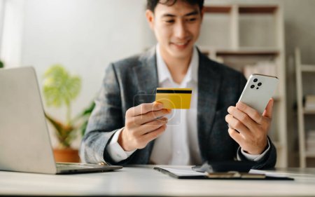 Foto de Hombre que utiliza el teléfono inteligente y la tarjeta de crédito para los pagos móviles compras en línea, omni canal - Imagen libre de derechos