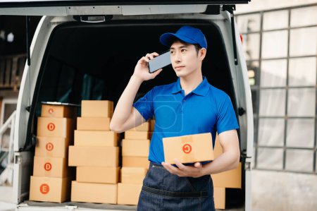 Téléchargez les photos : Happy delivery, Asian man standing  near van outside the warehouse. This is a freight transportation and distribution warehouse. - en image libre de droit