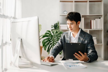 Foto de Young Asian businessman working at office with computer - Imagen libre de derechos