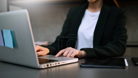Téléchargez les photos : Femme d'affaires avec ordinateur portable, téléphone intelligent et tablette PC au bureau - en image libre de droit
