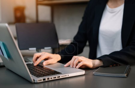 Téléchargez les photos : Femme d'affaires utilisant ordinateur portable et tablette au bureau - en image libre de droit
