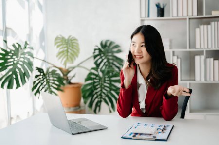 Foto de Negocio asiático mujer Hablando por teléfono y utilizando un ordenador portátil en casa oficina - Imagen libre de derechos