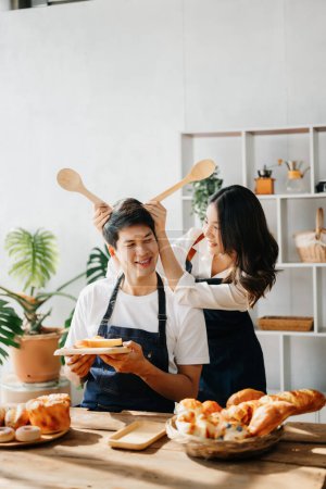 Foto de Amantes de Asia o pareja cocinando en cocina con pan en la mesa. - Imagen libre de derechos