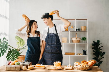 Téléchargez les photos : Les amoureux de l'Asie ou couple cuisine dans la cuisine avec du pain sur la table. - en image libre de droit