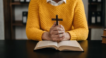 Hände zusammen im Gebet zu Gott zusammen mit der Bibel In der christlichen Vorstellung und Religion beten Frauen mit der Bibel auf dem schwarzen Tisch