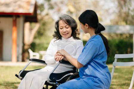 Photo for Elderly asian senior woman on wheelchair with Asian careful caregiver. Nursing home hospital garden concept. - Royalty Free Image