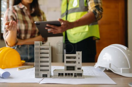 Photo for Two colleagues discussing data working and tablet  with  architectural project at construction site at desk in modern office - Royalty Free Image