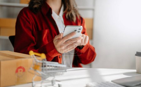 Foto de Mujer joven sosteniendo un teléfono inteligente que muestra el éxito del pago y la tarjeta de crédito con caja amarilla como concepto de compras en línea en la oficina - Imagen libre de derechos