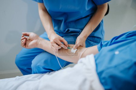  Amistosa enfermera jefa haciendo rondas hace chequeo del paciente que descansa en la cama. Ella comprueba la tableta mientras el hombre se recupera completamente después de una cirugía exitosa en un hospital