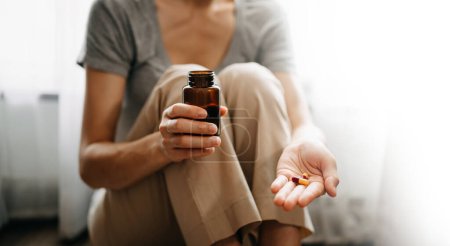 Téléchargez les photos : Femme tenant bouteille avec des pilules sur la main va prendre des médicaments - en image libre de droit