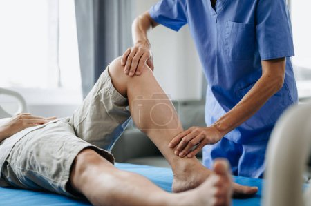 Foto de Primer plano del fisioterapeuta que trabaja con el paciente en la cama en la clínica - Imagen libre de derechos