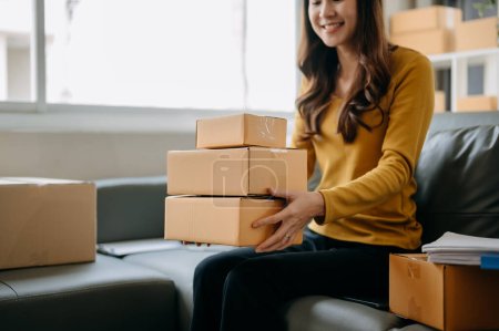 Foto de Joven empresaria mujer preparar cajas de paquetes y comprobar pedidos en línea para entregar al cliente - Imagen libre de derechos