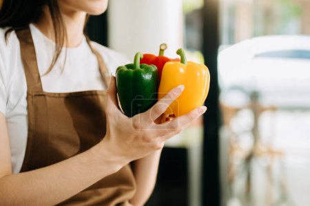 Photo for Fresh bell peppers holding by hands in the kitchen. - Royalty Free Image