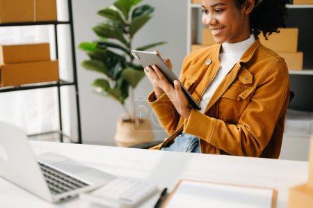 Téléchargez les photos : Entrepreneur PME freelance femme africaine travaillant au bureau à domicile et ordinateur portable en ligne, marketing, emballage, livraison, concept de commerce électronique - en image libre de droit
