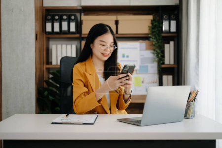 Téléchargez les photos : Asiatique femme d'affaires travaillant dans le bureau avec ordinateur portable et téléphone - en image libre de droit