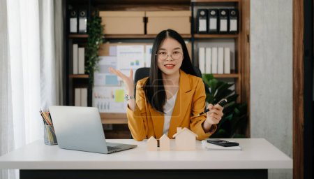 Téléchargez les photos : Jeune agent immobilier travailleur travaillant avec ordinateur portable dans un bureau moderne - en image libre de droit