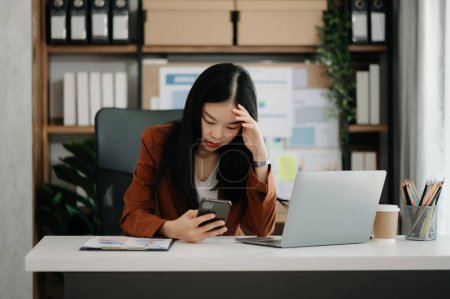 Téléchargez les photos : Femme asiatique se sentant migraine tête tendue.Overworked femme d'affaires financière avec sur ordinateur portable au bureau moderne. - en image libre de droit