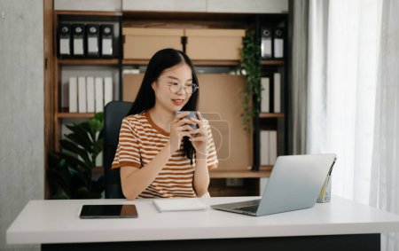 Foto de Chica asiática sentada en el escritorio usando ordenador portátil y tableta PC - Imagen libre de derechos