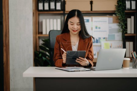 Téléchargez les photos : Femme d'affaires utilisant une tablette et un ordinateur portable au bureau - en image libre de droit