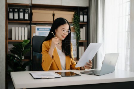 Téléchargez les photos : Femme d'affaires asiatique travaillant dans le bureau avec tablette et ordinateur portable dans le bureau moderne - en image libre de droit