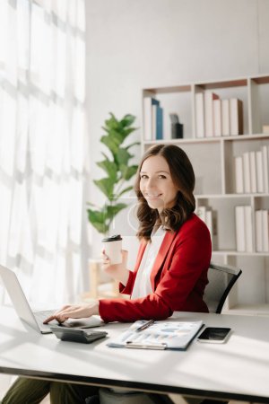 Téléchargez les photos : Femme confiante avec un sourire tenant un café au bureau moderne - en image libre de droit
