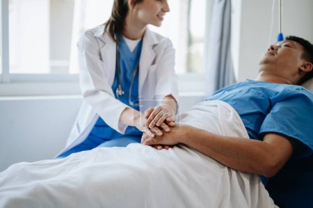 Téléchargez les photos : Femme médecin tenant la main du patient masculin sur le lit à l'hôpital - en image libre de droit
