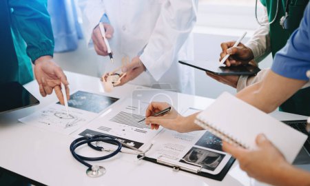 Photo for Medical team having a meeting with doctors in  lab coats  at a table discussing  patient ,working using computers in the medical industry - Royalty Free Image