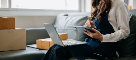 Téléchargez les photos : Femme utilisant tablette PC et ordinateur portable au bureau de son entreprise achats en ligne. Au bureau à domicile - en image libre de droit
