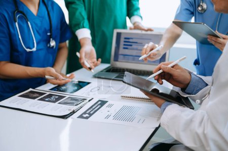 Téléchargez les photos : Équipe médicale en réunion avec des médecins en blouse de laboratoire à une table pour discuter du patient, travailler avec des ordinateurs dans l'industrie médicale - en image libre de droit