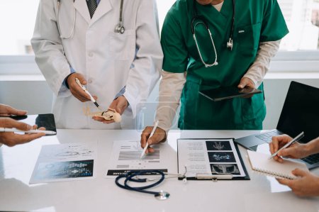 Téléchargez les photos : Équipe médicale en réunion avec des médecins en blouse de laboratoire à une table pour discuter du patient, travailler avec des ordinateurs dans l'industrie médicale - en image libre de droit