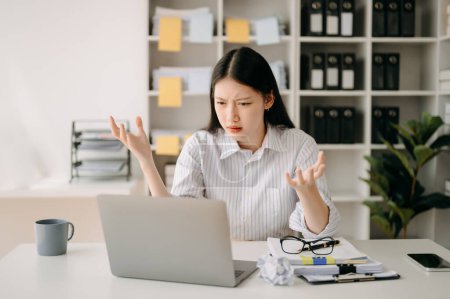 Foto de Mujer asiática sensación migraña cabeza strain.Overworked financiero mujer de negocios mientras trabajaba en el ordenador portátil en la oficina. - Imagen libre de derechos