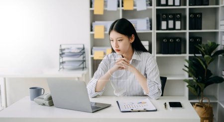Téléchargez les photos : Asiatique femme d'affaires travaillant dans le bureau avec ordinateur portable et téléphone dans le bureau moderne - en image libre de droit