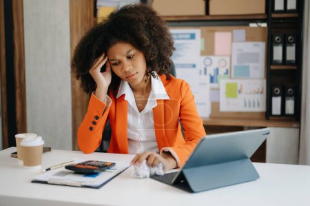 Afrikanische Geschäftsfrau ist gestresst, gelangweilt und überfordert von der Arbeit am Tablet im modernen Büro