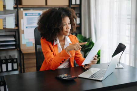 Téléchargez les photos : Femme africaine d'affaires utilisant tablette et ordinateur portable pour faire de la finance mathématique sur un bureau de bureau, impôt, rapport, comptabilité, statistiques, et concept de recherche analytique au bureau - en image libre de droit
