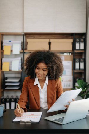 Téléchargez les photos : Confiant belle femme d'affaires africaine avec ordinateur portable a au bureau moderne - en image libre de droit