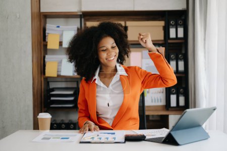 Téléchargez les photos : Femme d'affaires africaine sont ravis et heureux avec tablette PC et café au bureau à domicile - en image libre de droit
