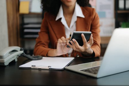 Téléchargez les photos : Femme d'affaires travaillant avec les finances sur le coût et la calculatrice et ordinateur portable au bureau - en image libre de droit