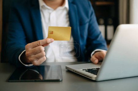 Téléchargez les photos : Homme utilisant la carte de crédit pour les paiements mobiles achats en ligne, omni canal et ordinateur portable - en image libre de droit