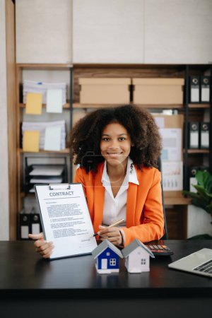 Téléchargez les photos : Jeune agent immobilier travailleur travaillant avec ordinateur portable à la table dans un bureau moderne - en image libre de droit